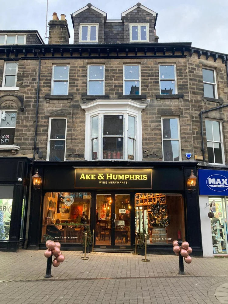 Storefront of Ake & Humphris with decorative balloons on a city street.