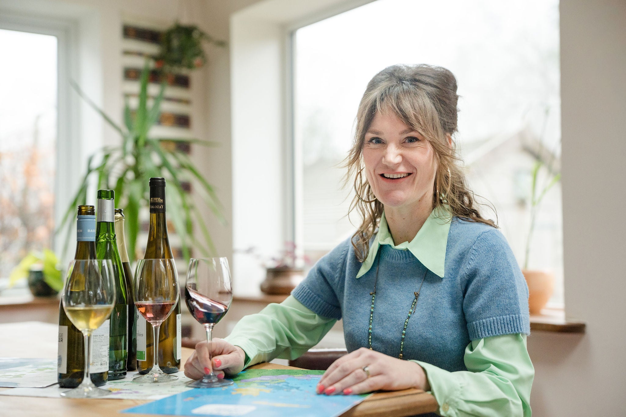 Sophia from The Drink Taking with wine maps and bottles of wine at table
