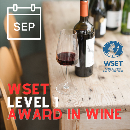Wine bottle and glass on a wooden table with WSET Level 1 Award in Wine text and logo.